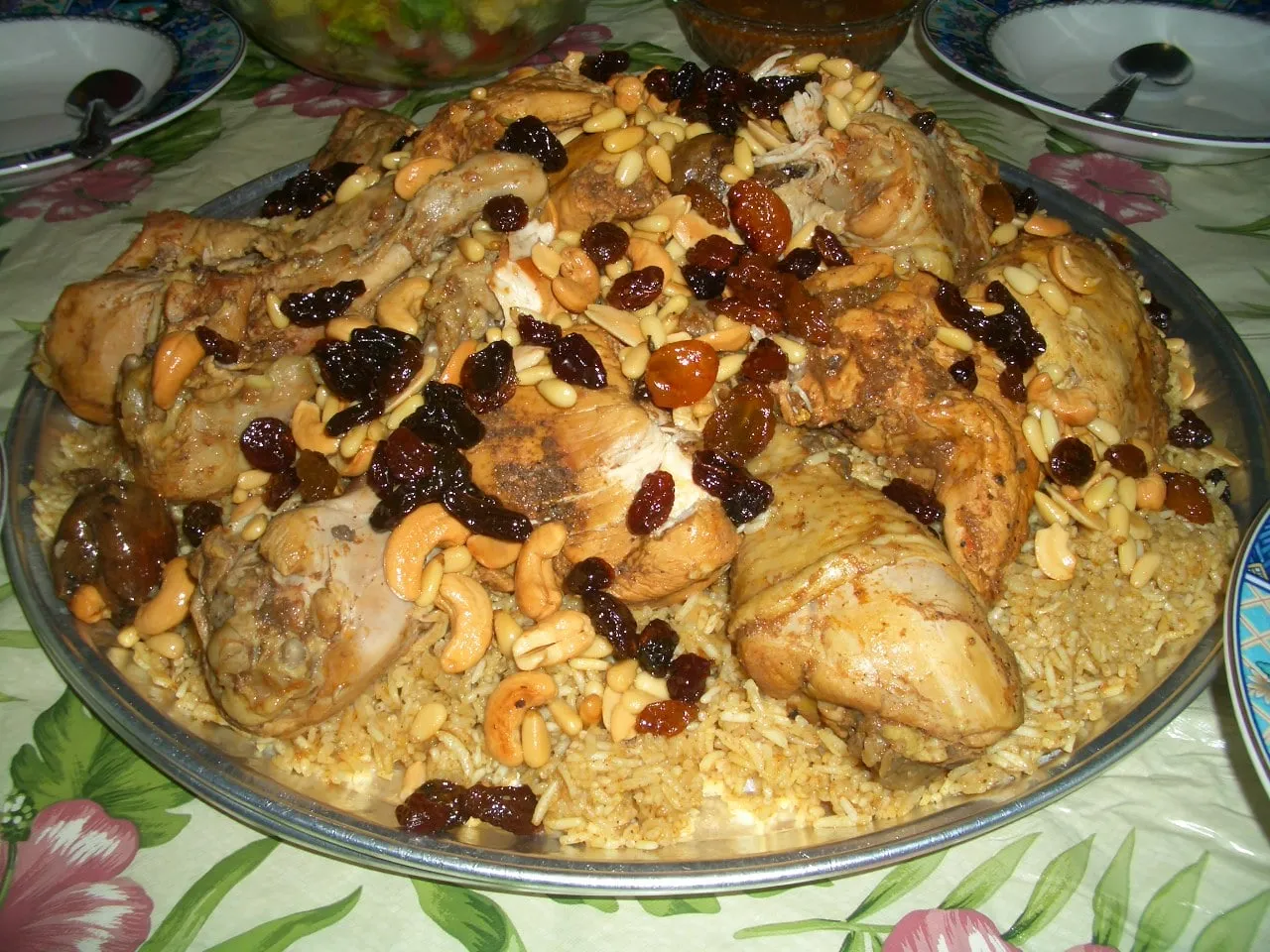 Saudi chicken kabsa on a large platter topped with fried nuts and raisins